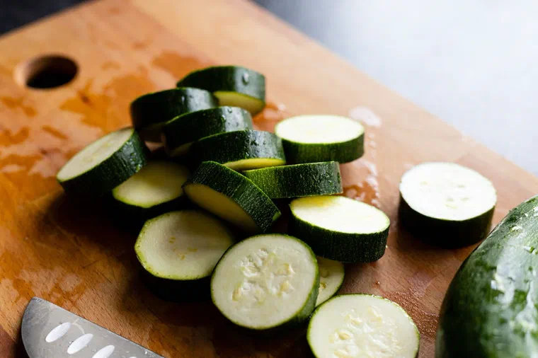 Des courgettes coupées en rondelles d'environ 1 cm sur une planche à découper en bois