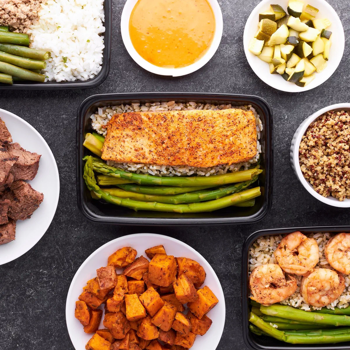 Plats préparés à l'avance vus de dessus : saumon sur riz et haricots verts, crevettes, cubes de patate douce, riz, courgettes et bœuf