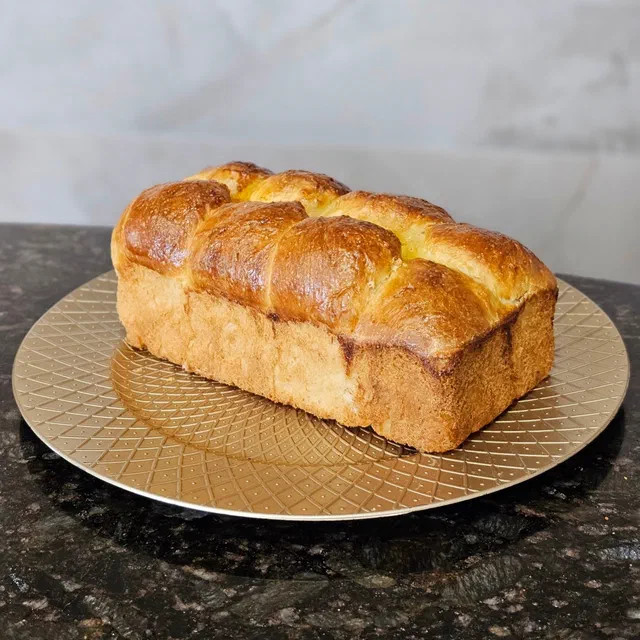 Une brioche Nanterre dorée aux boules soudées, cuite en moule à cake, posée sur un plat doré
