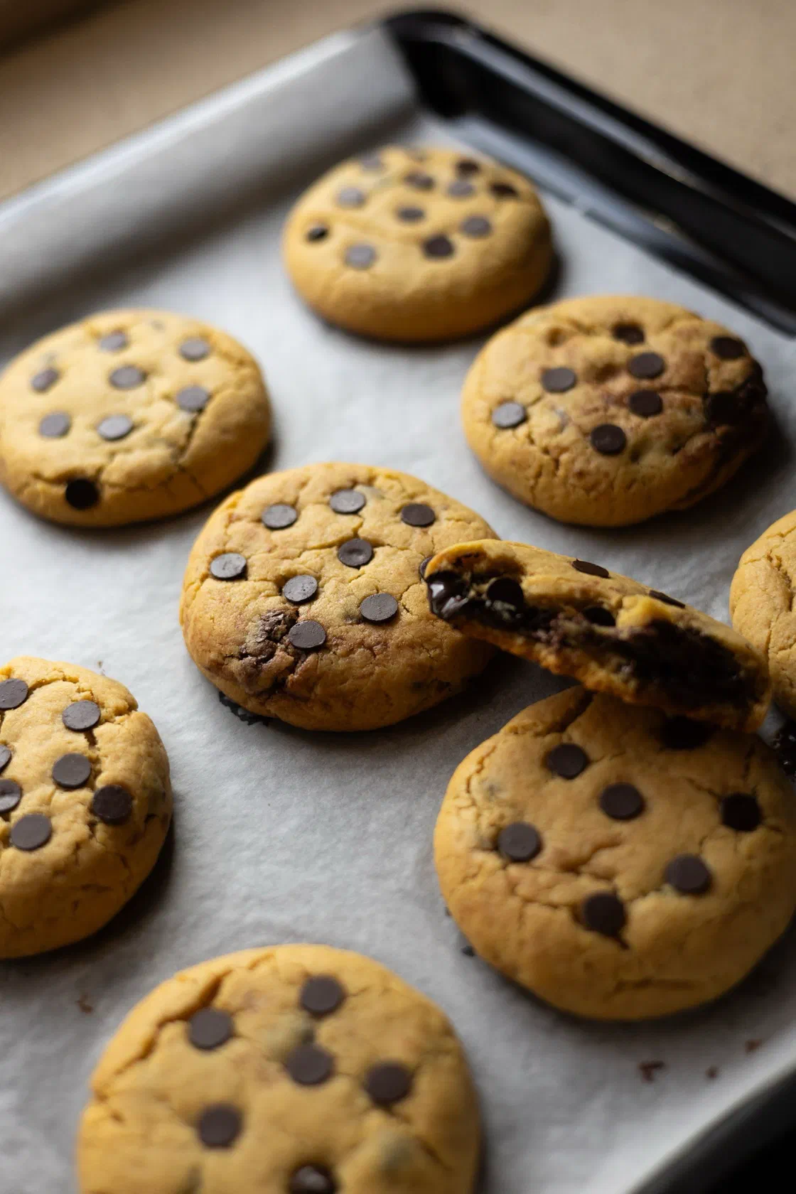 Des cookies aux pépites de chocolat juste cuits sur une plaque tapissée de papier cuisson