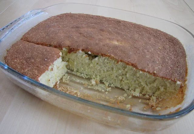 Un gâteau au yaourt doré dans un plat en verre, une part déjà coupée laisse voir la mie
