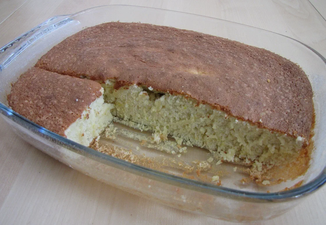 Un gâteau au yaourt doré dans un plat en verre, une part déjà coupée laisse voir la mie