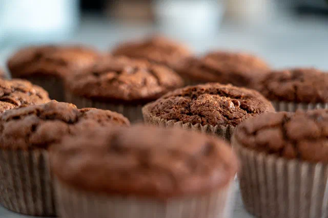 Des muffins au chocolat bombés et craquelés sur le dessus, dans leurs caissettes en papier