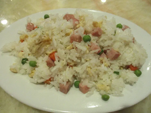 Une assiette de riz cantonais avec des dés de jambon, des petits pois, de l'œuf et quelques dés de carotte