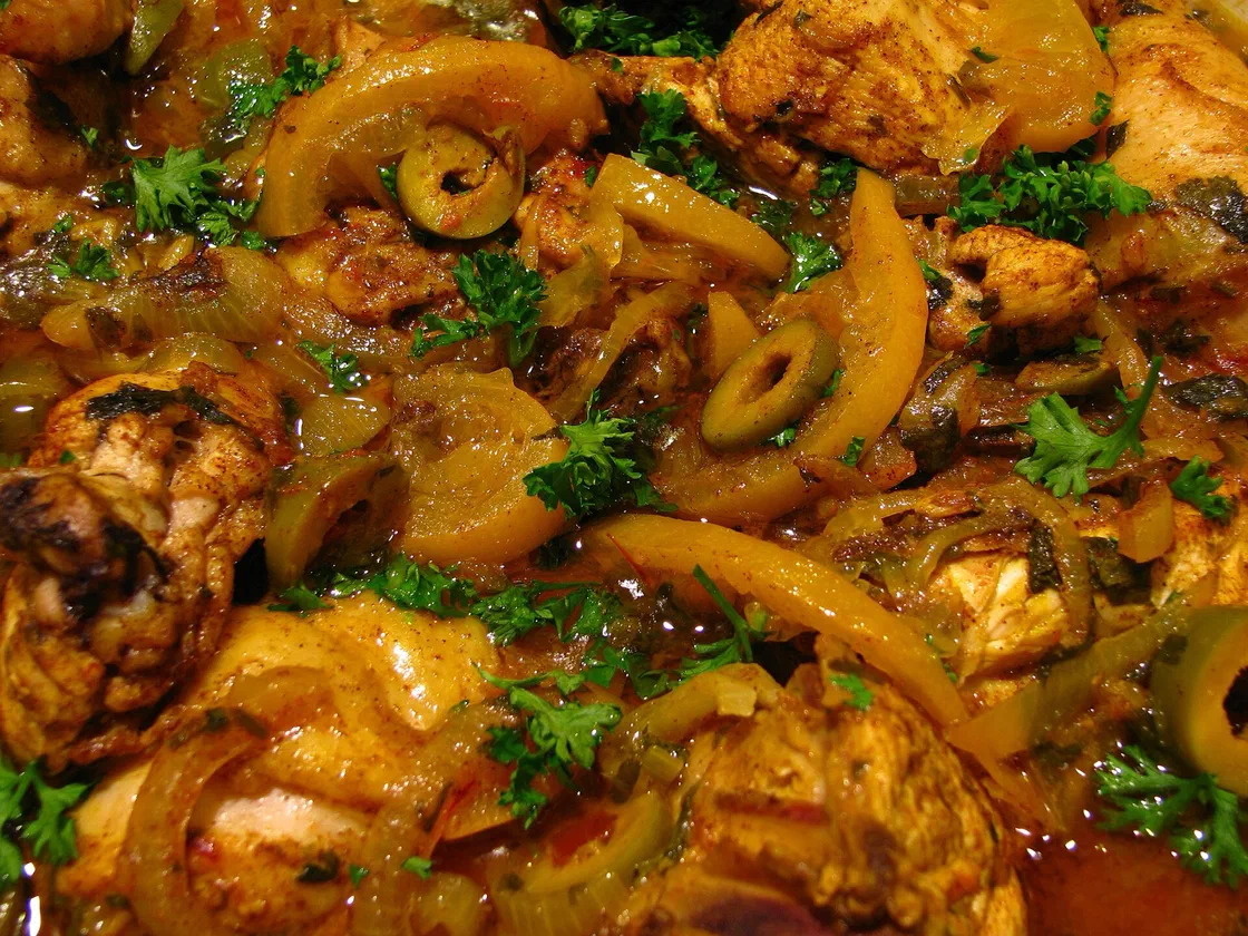 Morceaux de poulet en sauce dorée avec des lamelles de citron confit, des olives vertes et du persil